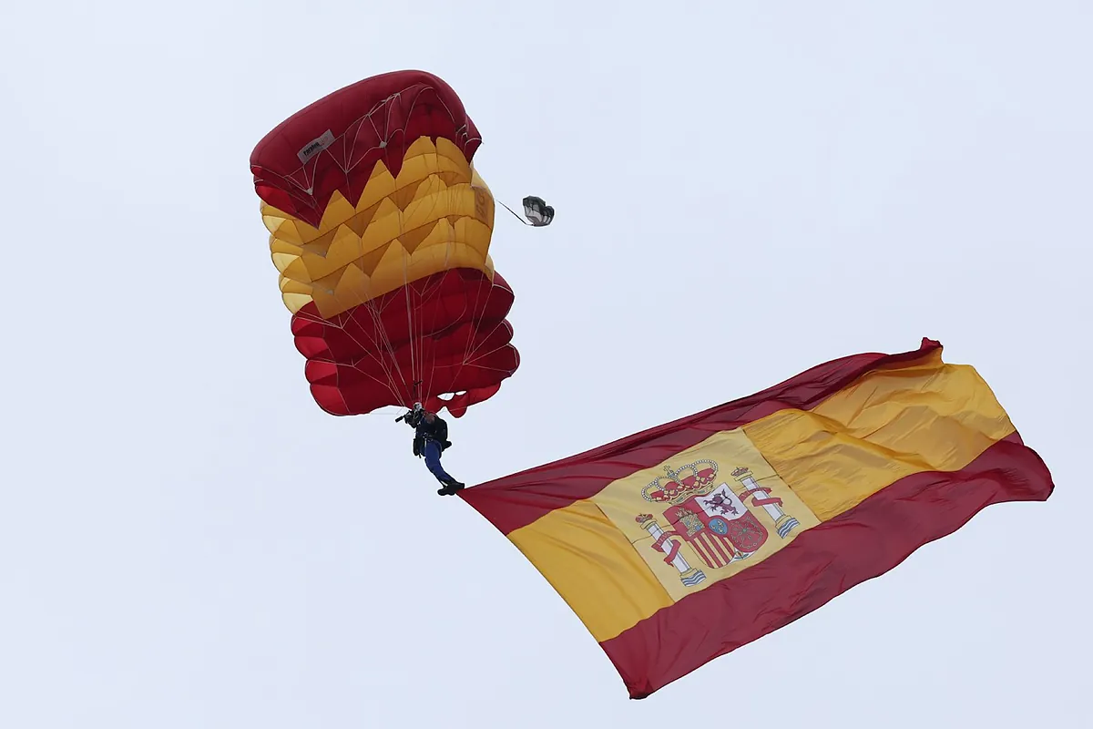 La bandera de España llega a tierra desde el aire gracias a la pericia de dos paracaidistas